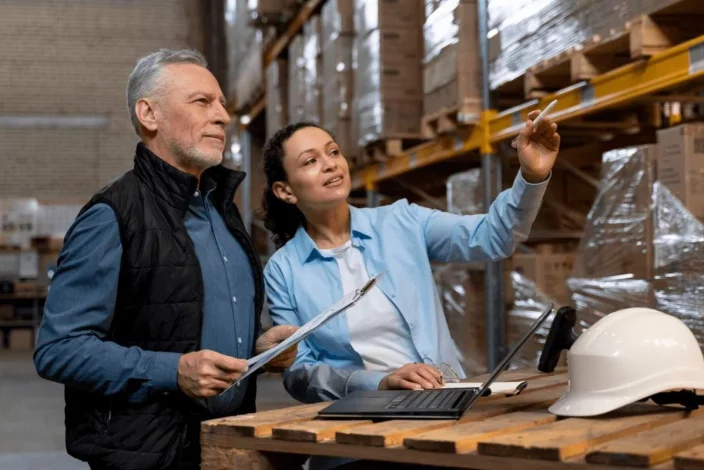 photo d'un homme et une femme discutant de planification logistique dans un entrepôt logistique