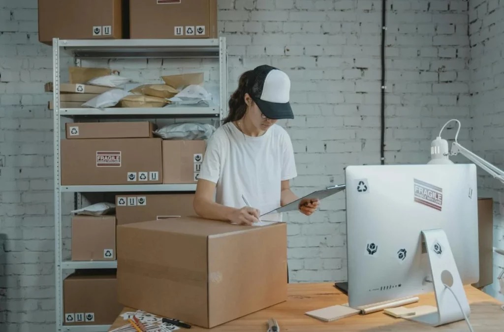 photo d'une femme faisant de l'ordonnancement logistique. Elle a des cartons et un ordinateur.